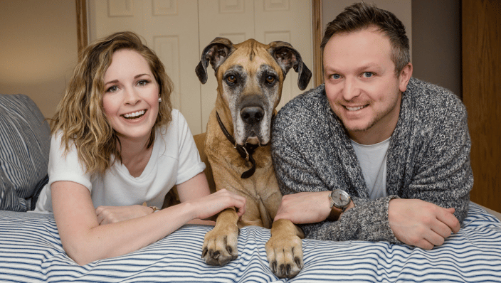 Couple laying on bed with Great Dane between them