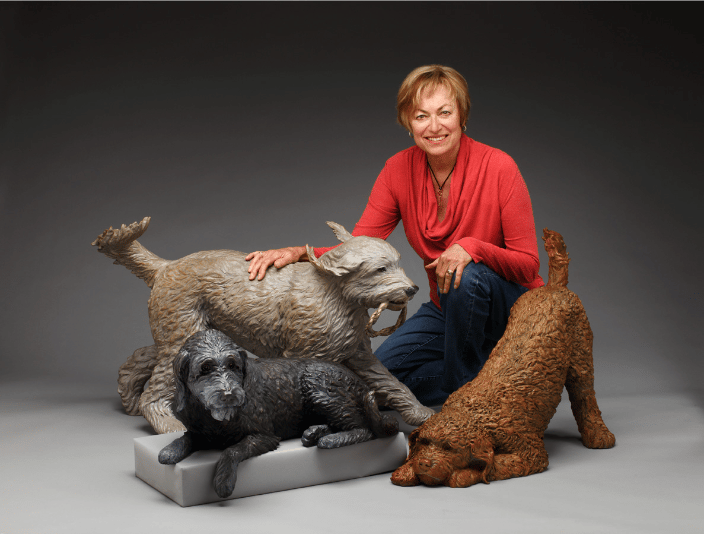 The artist with three labradoodle bronze portraits